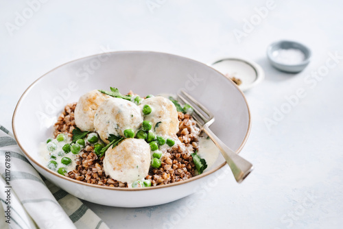 A nourishing bowl features turkey meatballs over a base of cooked grains and vibrant green peas, garnished with herbs, ready for a satisfying meal any time of day