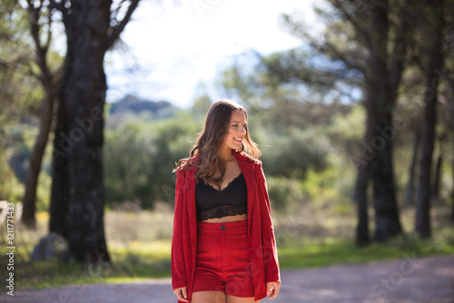 Beautiful brunette Latin woman walks among trees in a park while doing different facial and body postures and having fun. It is a sunny autumn day. photo