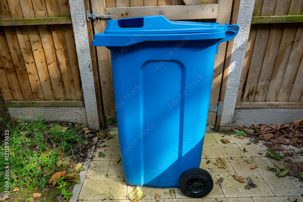 Obraz premium Blue Wheeled Recycling Bin in a Backyard