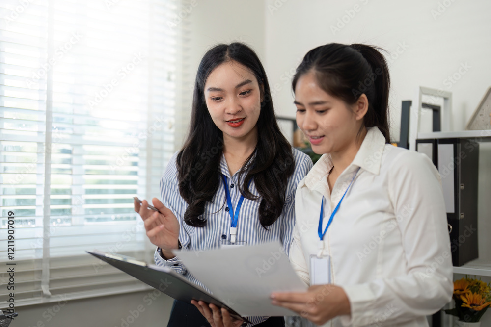 Collaborative businesswomen analyzing reports together and discussing insights in a bright and modern office Collaborative businesswomen analyzing reports together and discussing insights in a bright and modern office