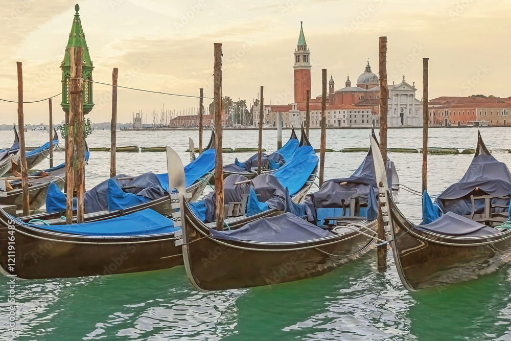 Colorful photo of Gondolas in Venice at dawn. The island of San Giorgio Maggiore with the basilica is in the background. Horizontally. Colorful photo of Gondolas in Venice at dawn. The island of San Giorgio Maggiore with the basilica is in the background. Horizontally.