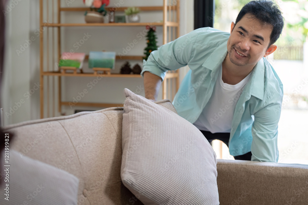 Obraz premium Gay couple relocating to their new home, one partner arranging furniture with a smile
