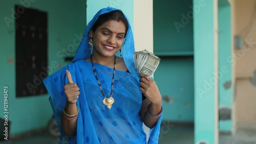 Happy Indian house wife proudly showing her last month's salary - working woman  financially independent villager. A portrait of a village woman holding 500 rupees notes from her saved earnings - h...