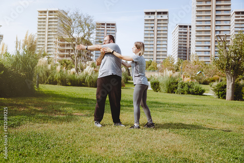 Man with extra weight doing work-up in public park with his trainer.  photo