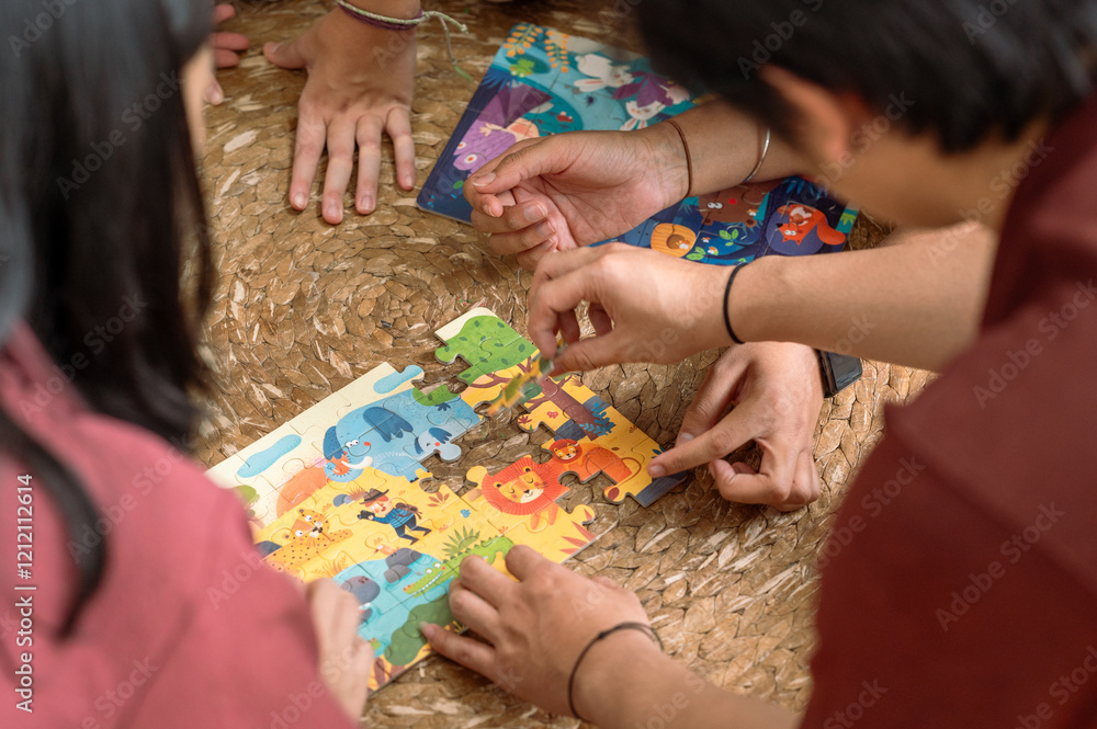 Close-up of Asian hands collaborating to assemble a colorful animal-themed puzzle on a woven surface. The scene showcases teamwork, problem-solving, and creativity in a cozy indoor setting Close-up of Asian hands collaborating to assemble a colorful animal-themed puzzle on a woven surface. The scene showcases teamwork, problem-solving, and creativity in a cozy indoor setting