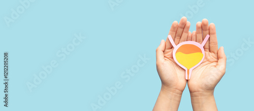 Hands holding bladder organ shape made from paper on light blue background. Awareness of bladder cancer, urinary tract infection, urinary incontinence and overactive bladder.