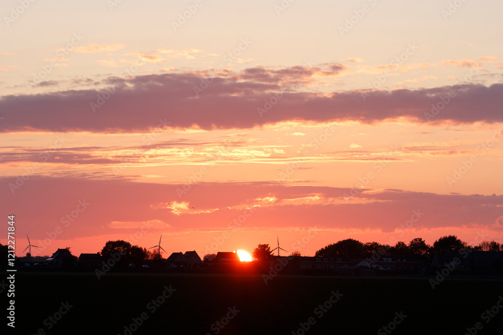Beautiful sunset over a landscape with wind turbines and trees creating a peaceful evening atmosphere Beautiful sunset over a landscape with wind turbines and trees creating a peaceful evening atmosphere