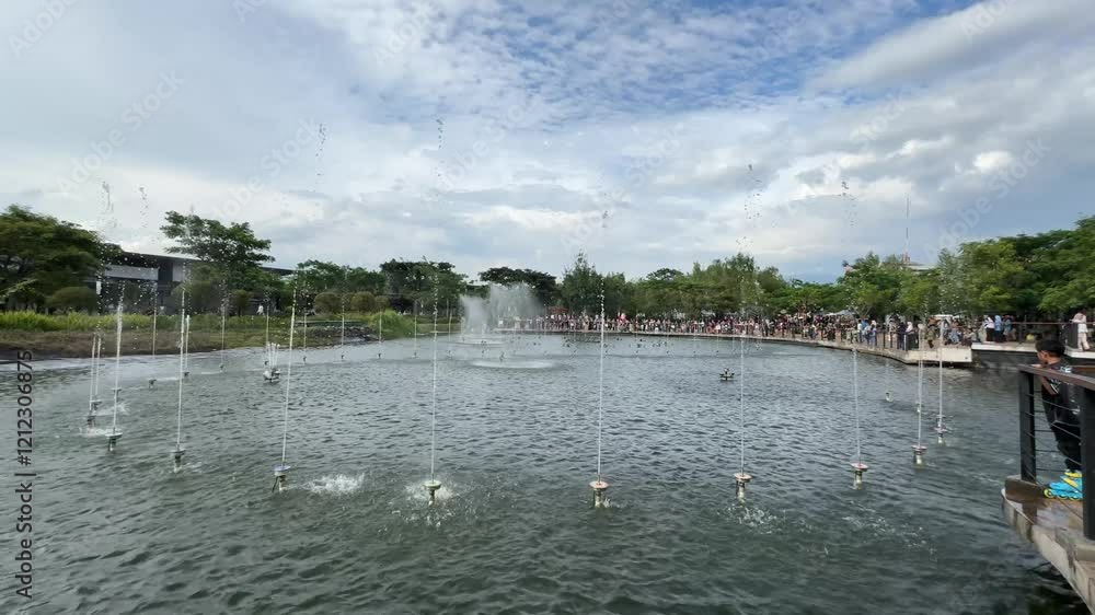 a scenic view of illuminated dancing water fountains at Kiara Artha Park on a bright sunny day. modern urban park in Bandung with a special show on the lake a scenic view of illuminated dancing water fountains at Kiara Artha Park on a bright sunny day. modern urban park in Bandung with a special show on the lake