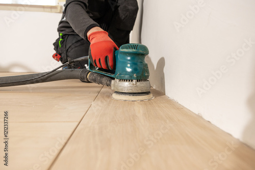 Cuadro en lienzo A person in dark work attire uses a green floor sander with a black hose to polish a wooden floor