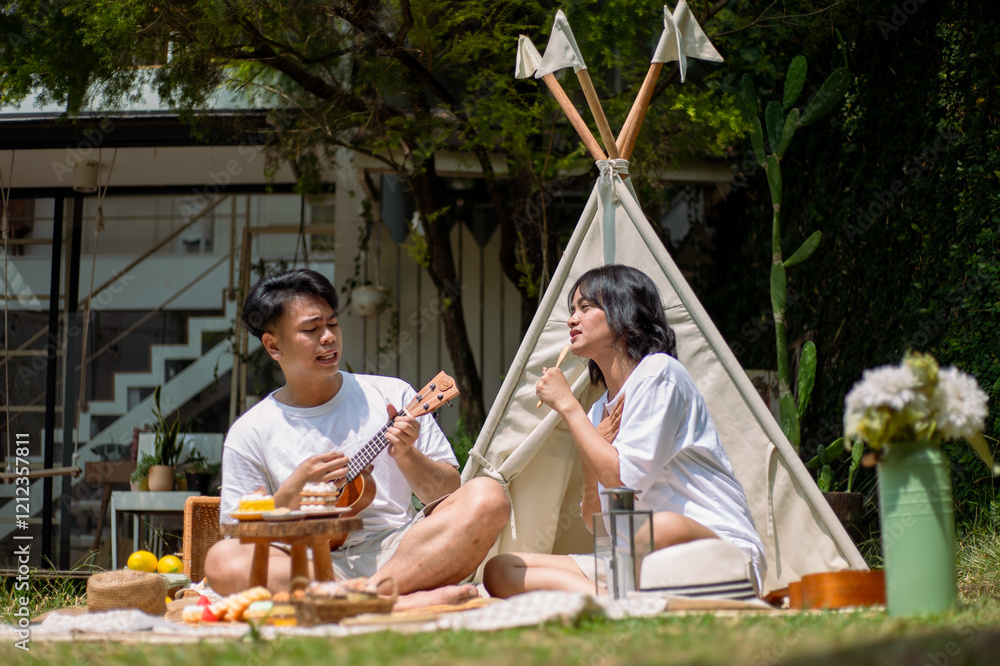 Asian couple enjoying a lively picnic in a serene garden setting. The man plays a ukulele while the woman enthusiastically sings and holds a popsicle, surrounded by desserts, fruits, and rustic decor Asian couple enjoying a lively picnic in a serene garden setting. The man plays a ukulele while the woman enthusiastically sings and holds a popsicle, surrounded by desserts, fruits, and rustic decor