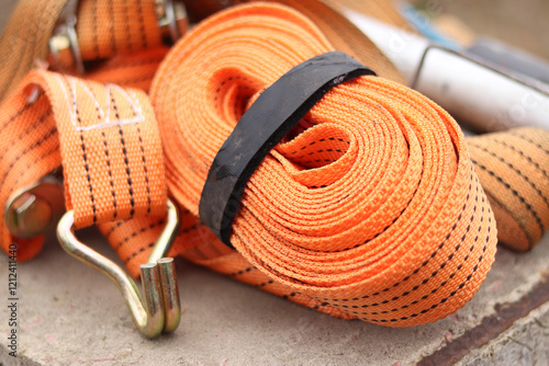 Lashing straps. Trailer strap made of orange nylon and metal tie. Close-up of a load holding strap. Cargo tie down strap. Cargo tie down fastening mechanism