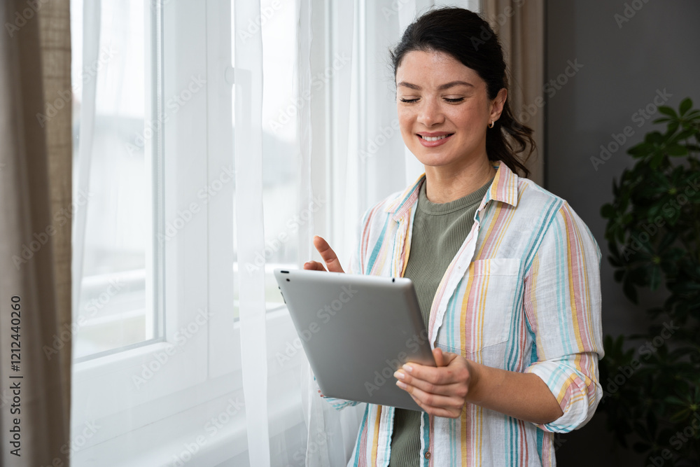 Attractive woman working on a digital tablet in a home office. Businesswoman small company owner work online from her apartment. Independent freelance graphic designer female enjoying freedom and job. Attractive woman working on a digital tablet in a home office. Businesswoman small company owner work online from her apartment. Independent freelance graphic designer female enjoying freedom and job.
