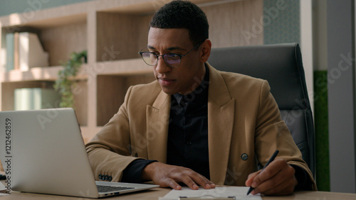 African American man accountant businessman manager analyst write notes data information writing business budget project report paperwork in office studying online with laptop educational course smile