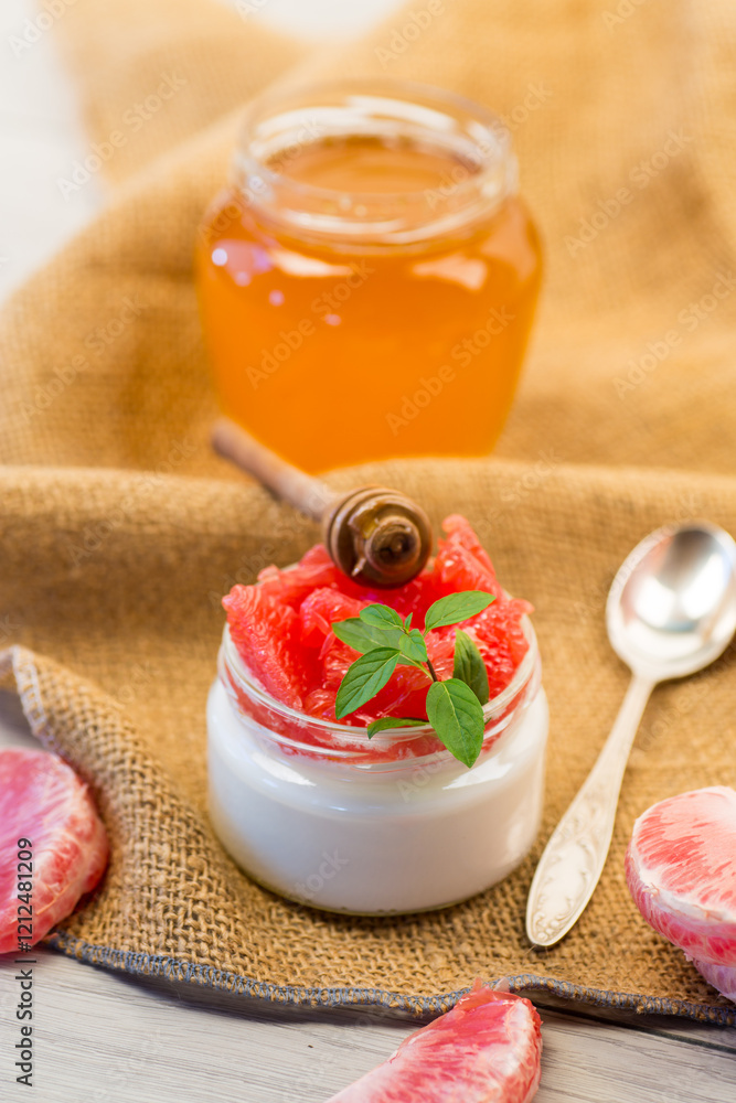 Φωτογραφία homemade sweet yogurt in a glass jar with pieces of red ripe grapefruit and hone