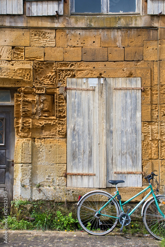 Hausfassade aus altem Sandstein mit Fahrrad in Marville, Grand Est, Frankreich