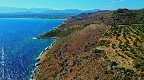 Breathtaking aerial view of Afrata Beach's rugged coastline with turquoise waters, dry rocky terrain and distant mountain ranges in Crete, Greece photo