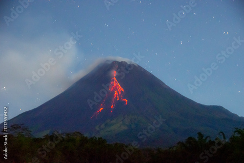 The peak of Mount Merapi spewing incandescent lava down its slopes at night, one of the most active volcanoes on the island of Java.