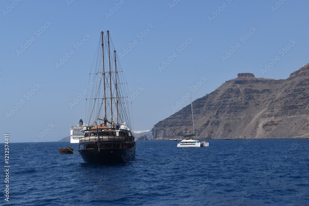 A luxury yacht and sail boat cruising in the crater of Santorini Island in the Mediterranean Sea, Greece A luxury yacht and sail boat cruising in the crater of Santorini Island in the Mediterranean Sea, Greece