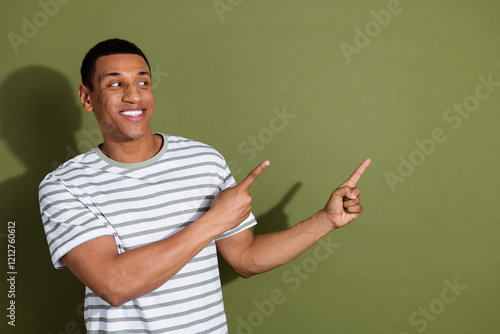 Photo of handsome good mood guy wear striped t-shirt looking showing two fingers emtpy space isolated khaki color background photo