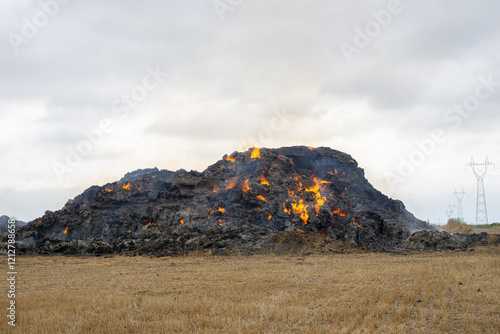 Burning straw on a meadow with smoke and close to the power line photo