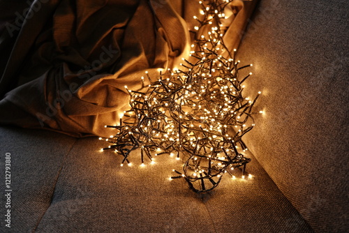 Warm christmas lights illuminating cozy sofa with blanket