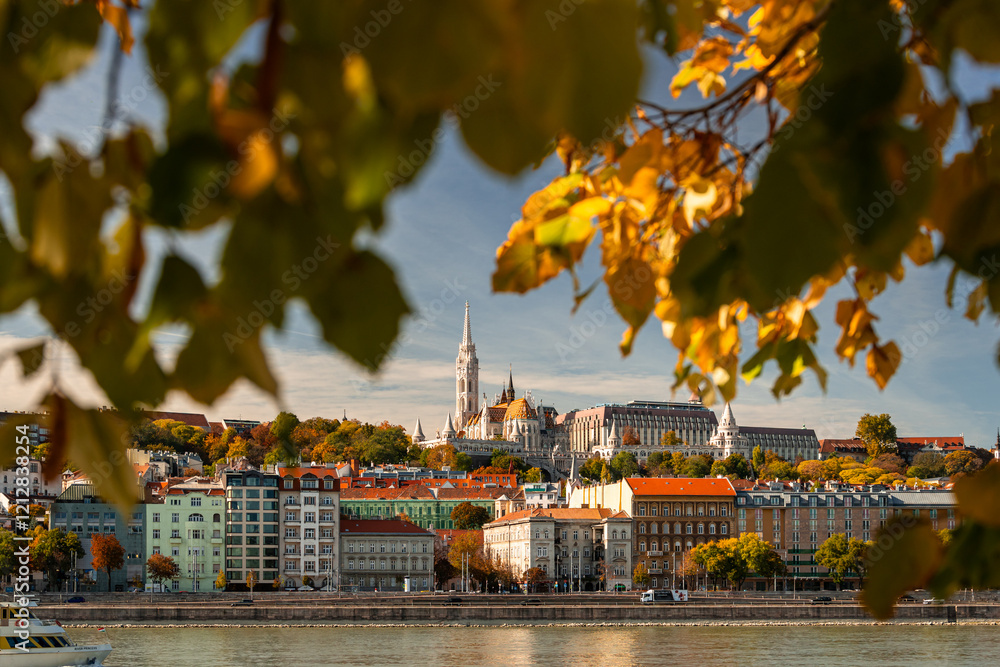 Autumn view of Danube river from Budapest rooftops, framed by golden leaves. A vibrant and iconic cityscape. Travel to Hungary.