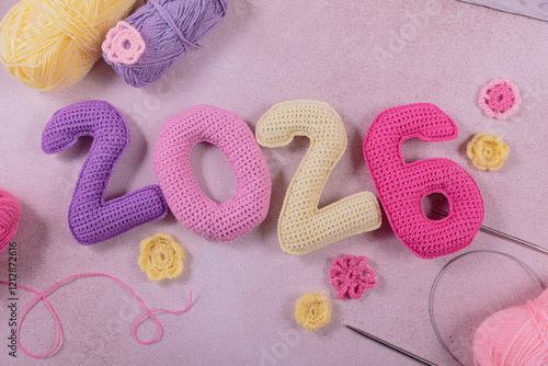 New Years background 2026. Multicolored crochet numbers, skein of wool yarn and knitting needles on gray background. New Years start creative handcrafted idea for DIY crafters photo