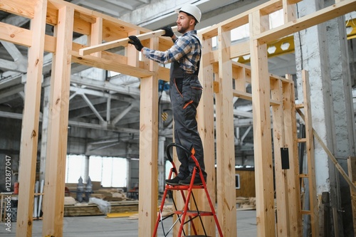 Portrait of a carpenter smiling with crossed arms in a lumber warehouse, showcasing expertise in the modular building industry photo