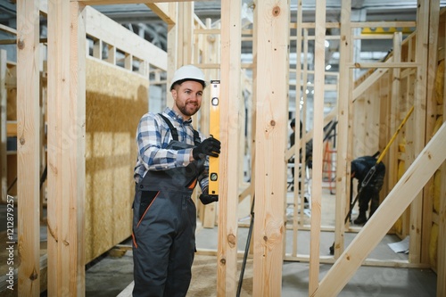 Portrait of a carpenter smiling with crossed arms in a lumber warehouse, showcasing expertise in the modular building industry photo