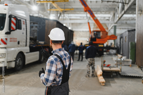 A worker controls the process of loading a modular house onto a truck. Transportation and delivery concept