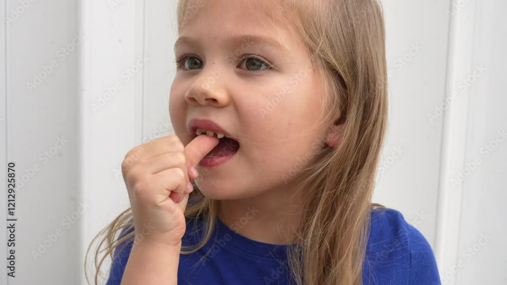 Cute Caucasian preschool girl wiggling her baby tooth with her finger which is ready to fall off. Dentistry concept. Happy healthy child about to lose a tooth