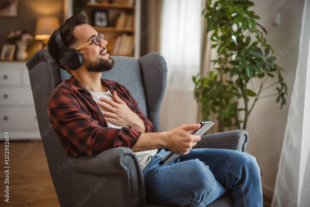 man with headphones sit in the armchair use tablet for work or fun man with headphones sit in the armchair use tablet for work or fun