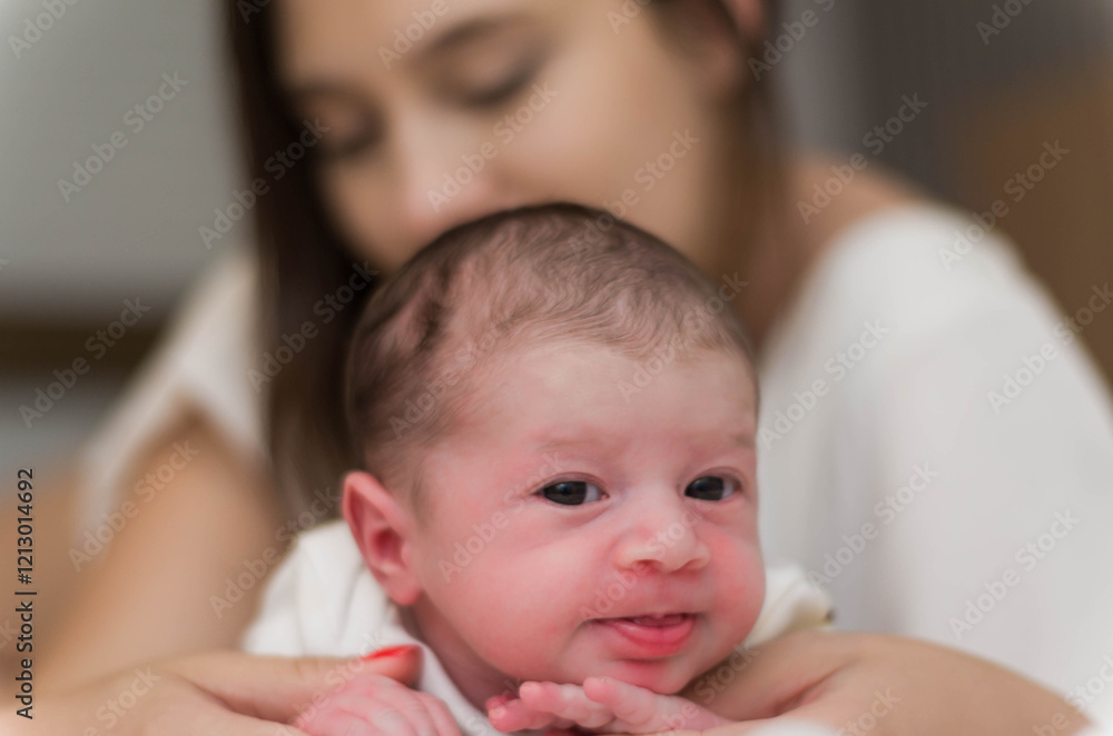 Young caring mother playing with her newborn son on the bed, hap Young caring mother playing with her newborn son on the bed, hap