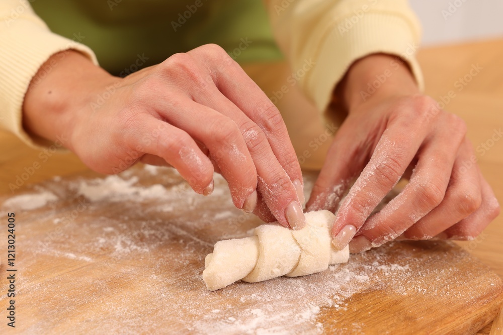Woman making croissant at wooden table, closeup Woman making croissant at wooden table, closeup