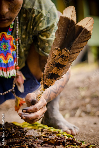 Sao Paulo, SP, Brazil - April 20 2023: Human hands dirty with paint holding bird feathers, indigenous event details. photo