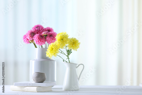 Beautiful flowers in vases and books on white wooden table at home. Space for text