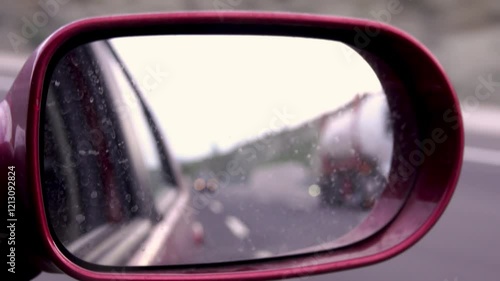 A shaky view of the highway from a dirty car mirror. A melancholic journey on a foggy road. Long way traffic with original audio track.
