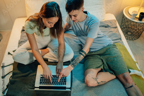 Lesbian couple browsing internet on laptop in bedroom photo