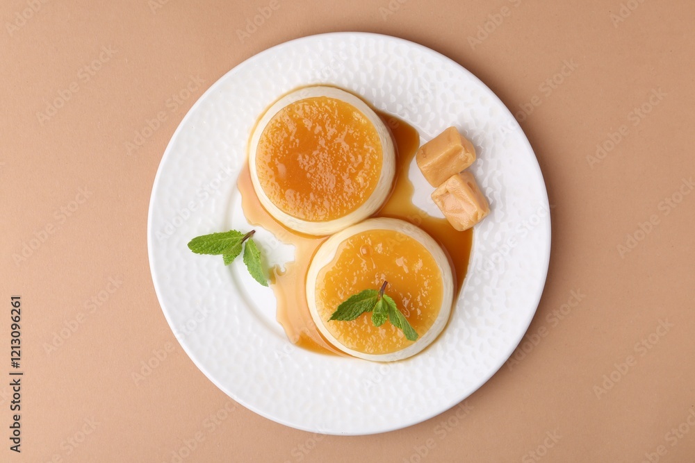 Tasty puddings with caramel sauce served on light brown background, top view