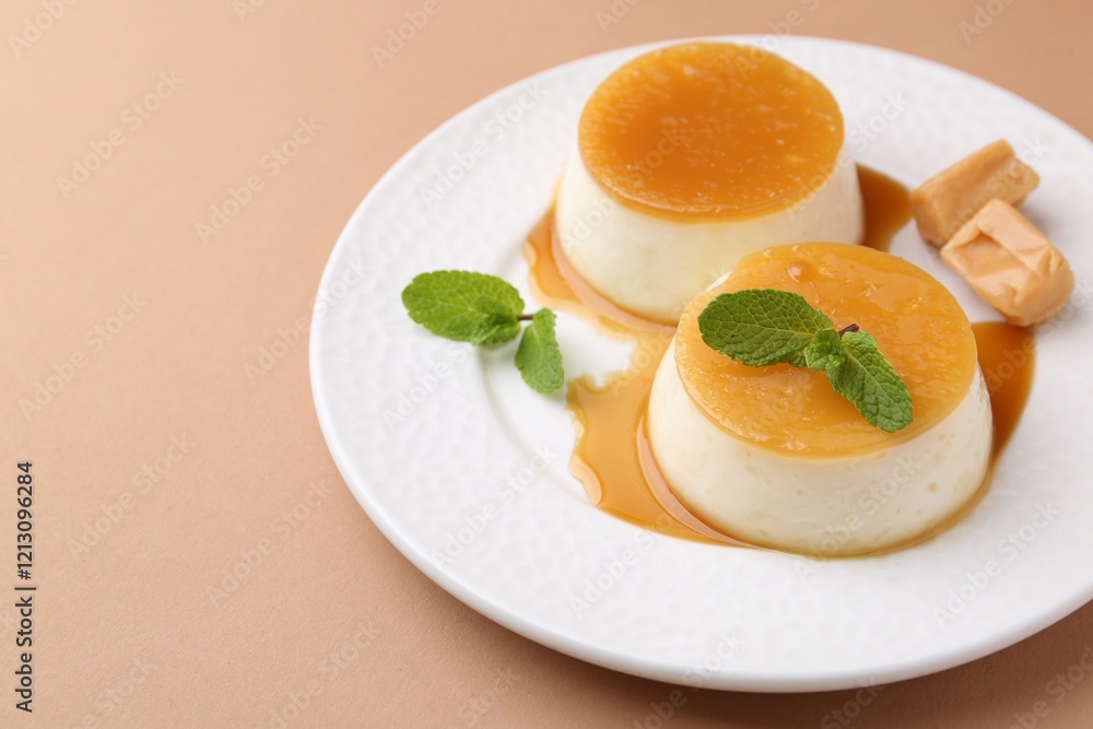 Tasty puddings with caramel sauce served on light brown background, closeup. Space for text Tasty puddings with caramel sauce served on light brown background, closeup. Space for text