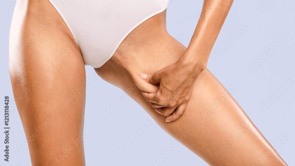 Skin Elasticity Check Concept. Closeup cropped view of unrecognizable young woman pinching her inner thigh, examining cellulite, wearing white panties isolated over blue studio background, banner Skin Elasticity Check Concept. Closeup cropped view of unrecognizable young woman pinching her inner thigh, examining cellulite, wearing white panties isolated over blue studio background, banner