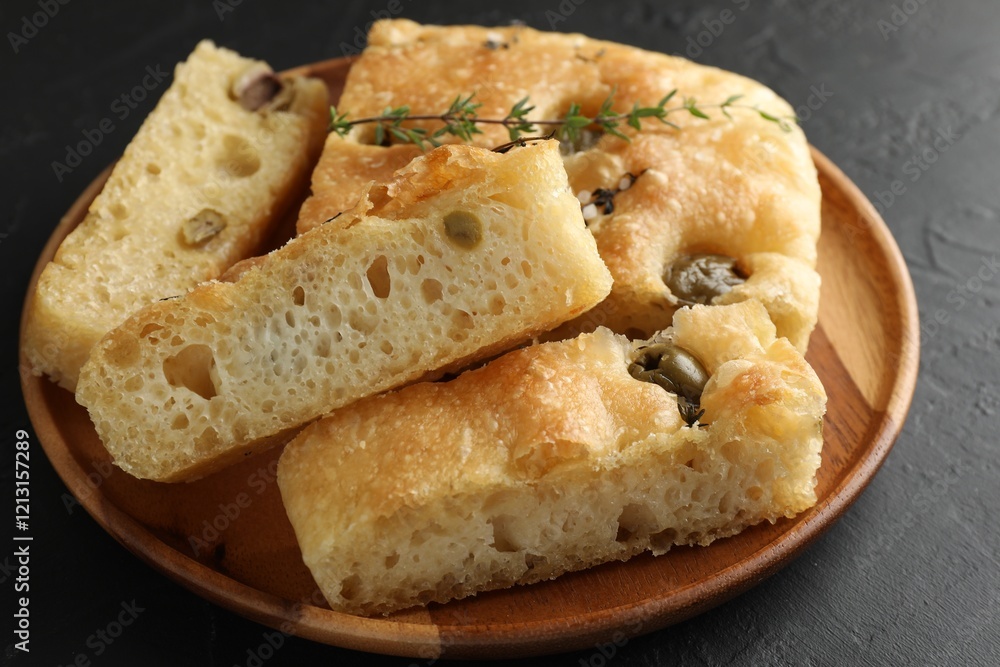 Slices of delicious focaccia bread with olives, thyme and salt on black table, closeup Slices of delicious focaccia bread with olives, thyme and salt on black table, closeup