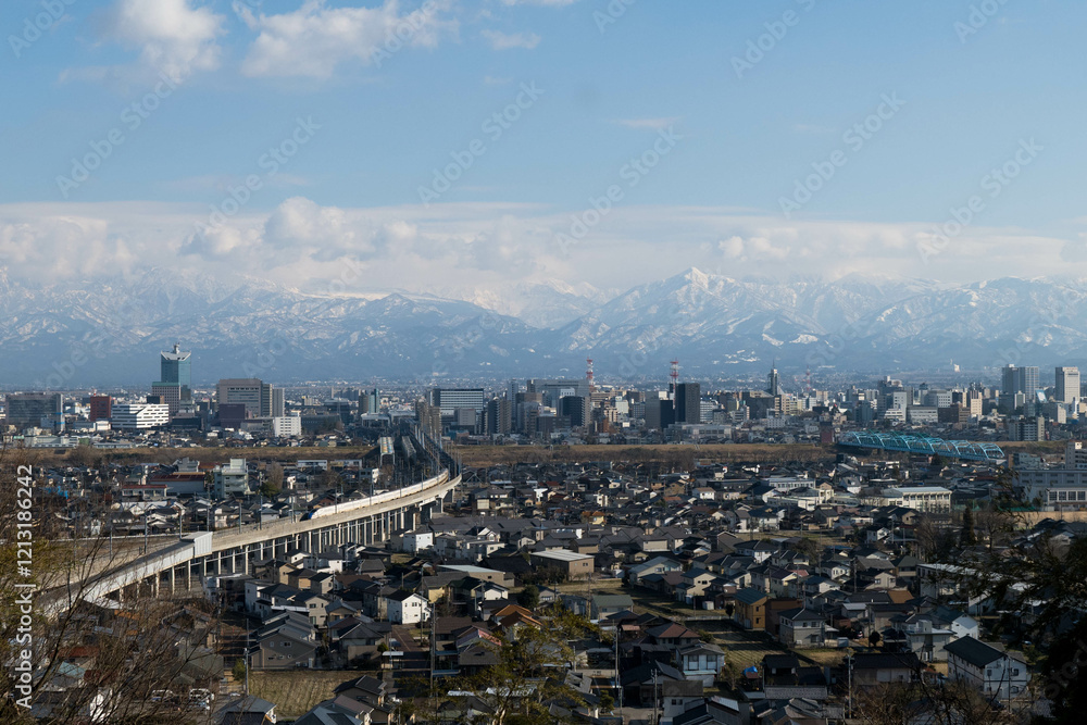 Obraz premium 冬の富山市市街地中心部と鍬崎山、富山駅の背後にラムサール条約登録の雪の弥陀ヶ原も見える富山市市街地