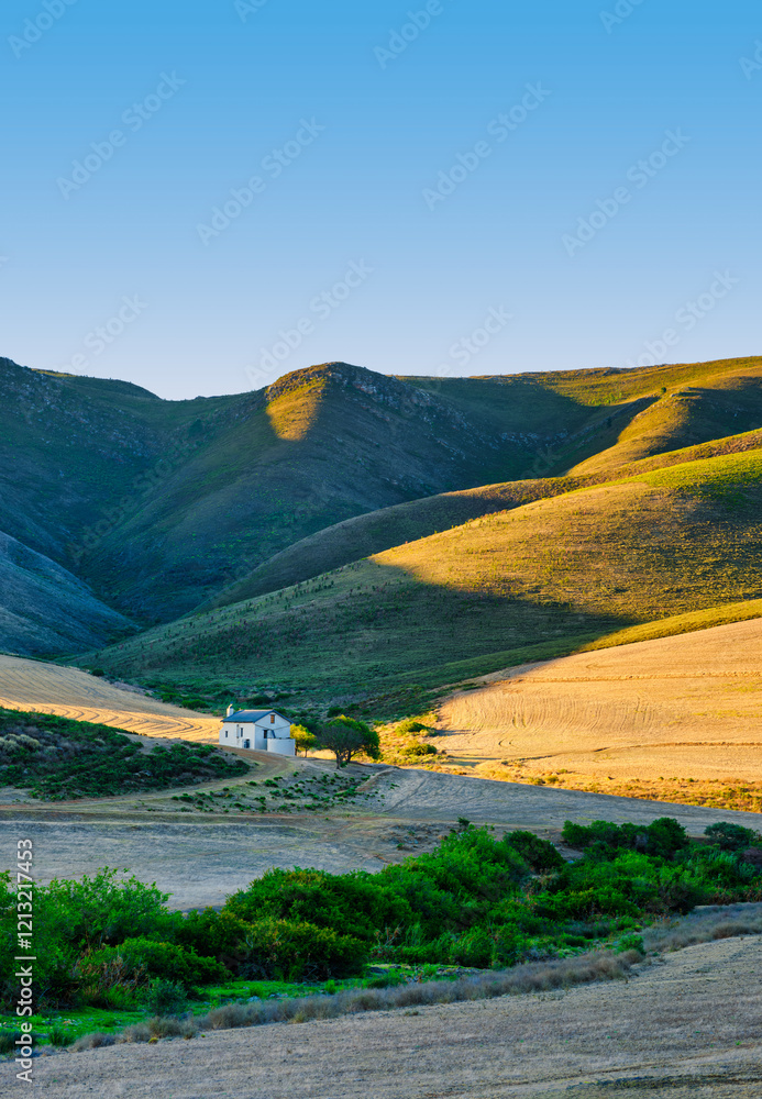 Vertical shot of a farmhouse amidst rolling hills in the Overberg, Caledon, South Africa