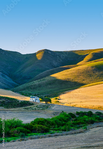Obraz na płótnie Vertical shot of a farmhouse amidst rolling hills in the Overberg, Caledon, South Africa w salonie