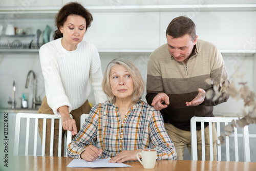 Middle-aged family members partitioning inheritance with mother sitting at kitchen-table with a sheet of paper and pen in hand photo