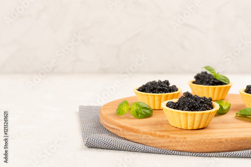 Canvas Print Tartlets with black caviar served on on wooden table