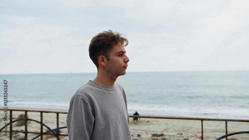 Boy Looks With Neutral Expression Towards The Ocean On A Gloomy Day Boy Looks With Neutral Expression Towards The Ocean On A Gloomy Day