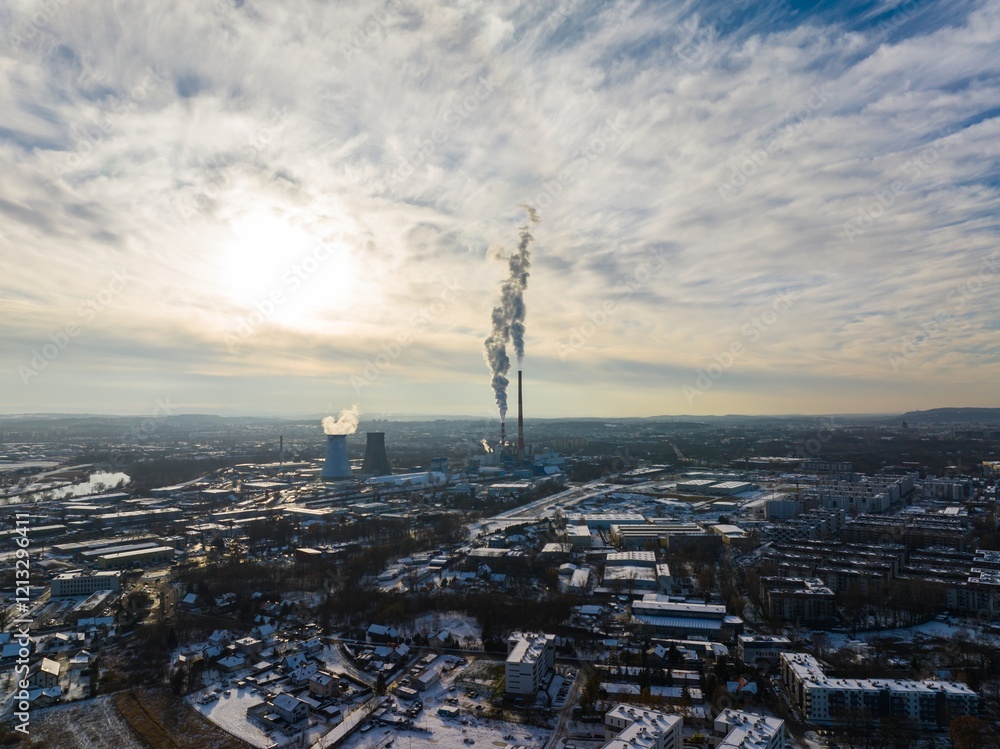 Fototapeta premium Industrial landscape with smokestacks emitting smoke at sunset near a city in winter