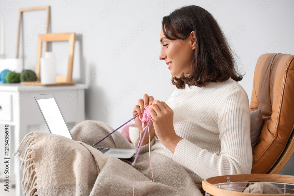 © Pixel-Shot - Young woman knitting with needles and laptop at home © Pixel-Shot - Young woman knitting with needles and laptop at home